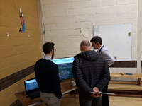 SSEN Transmission employees and a member of the public examining a visualisation on a screen.