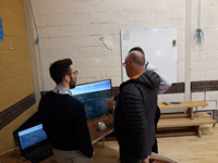 SSEN Transmission employees and a member of the public examining a visualisation on a screen.