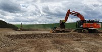 Construction vehicles atop a raised dirt area.