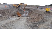 An excavator next to an excavated trench.