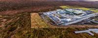 An aerial view of a substation under construction in a rural area.