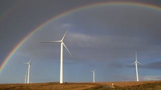 Landscape of wind turbines with a rainbow in the background