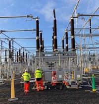 Contractors in PPE next to substation infrastructure.