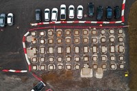 An overhead view of a dirt area on a construction site.  Concrete squares are placed at intervals across the area. Contractors in PPE stand between the concrete squares.