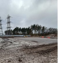 A gravel and dirt area next to a substation.