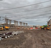 Construction vehicles surrounded by substation infrastructure.