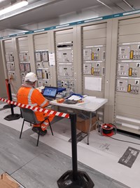 Contractors in PPE sat with a laptop next to a bank of machines.