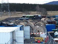 Large round wooden cylinders, stored next to stacks of other construction supplies.