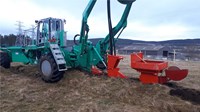 A wide construction vehicle with four wheels, at the rear of the vehicle is a plough device, partially submerged in the ground.