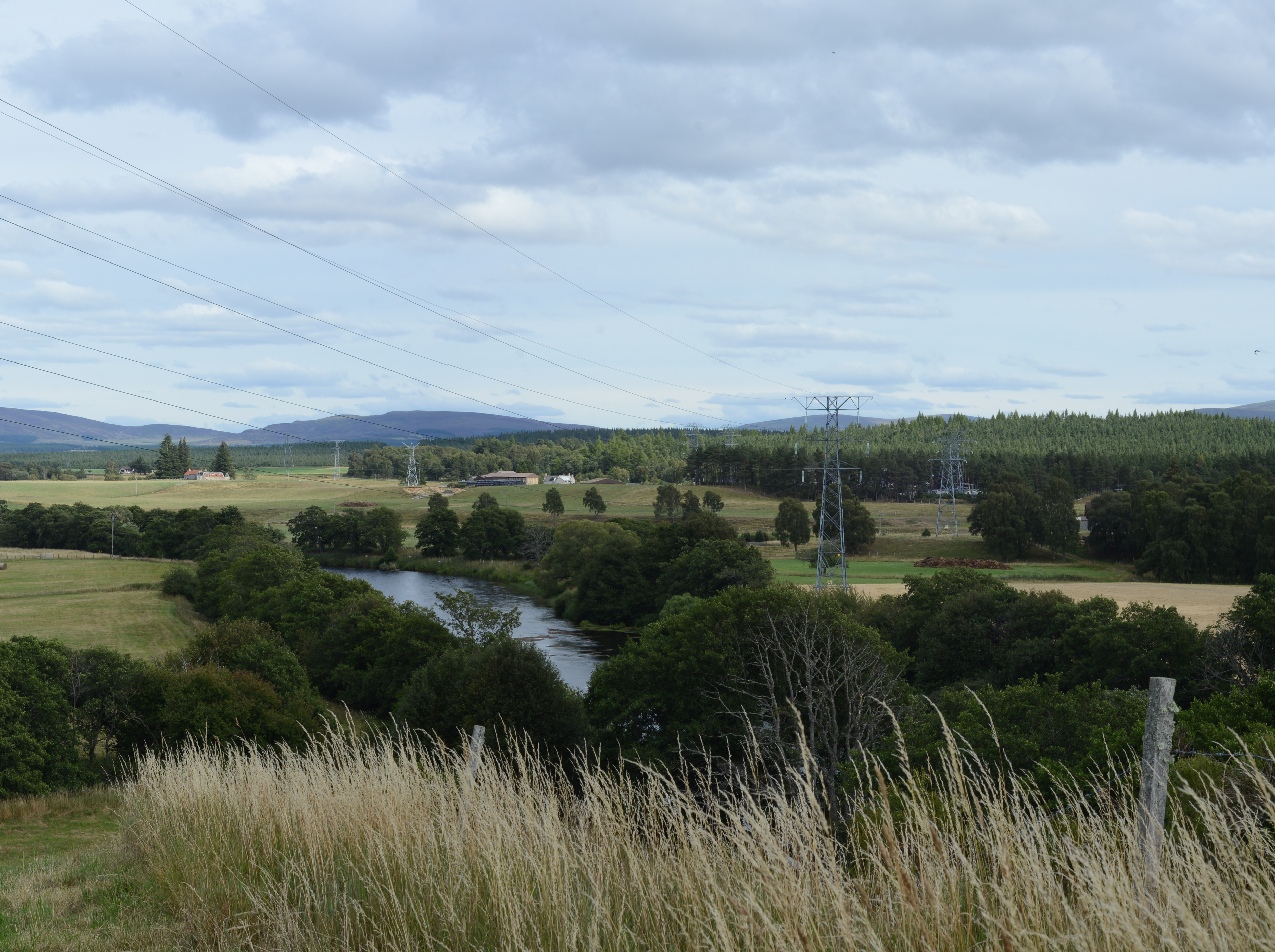 Metal transmission towers forming an overhead line in a rural area.