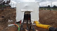 A material wrapped structure in an excavated area, cabling leads into the structure.