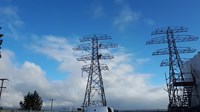 Contractors in PPE atop metal transmission towers.