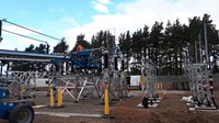 Contractor in PPE atop substation infrastructure.