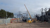 Substation infrastructure suspended from a crane arm.