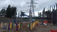 A contractor on a mobile platform in the air next to substation infrastructure.