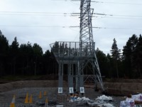 A metal platform structure at the base of a metal tranmission tower.