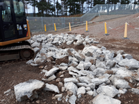 Rocks on the ground near an excavator.