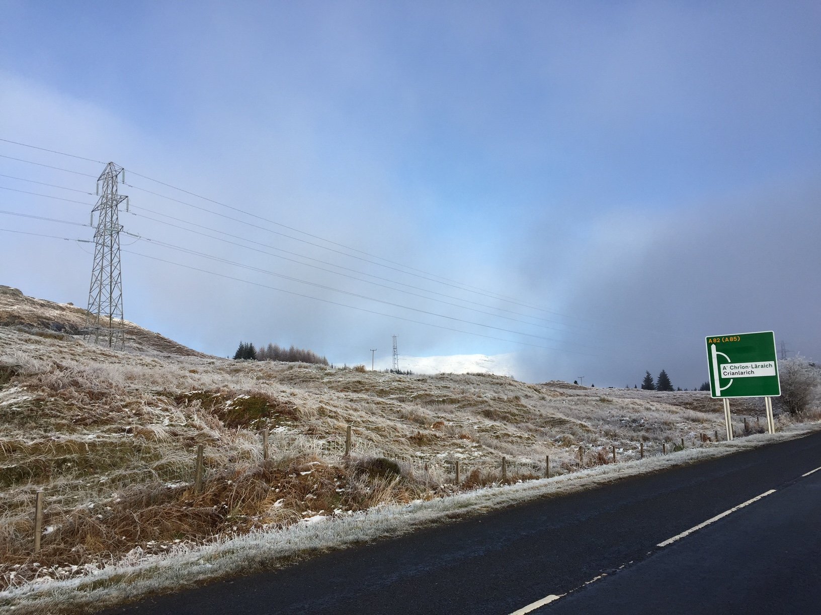 A frosted bank next to a road, a sign reads  "A82 (A85)", and "A Crion Laraich / Crianlarich".