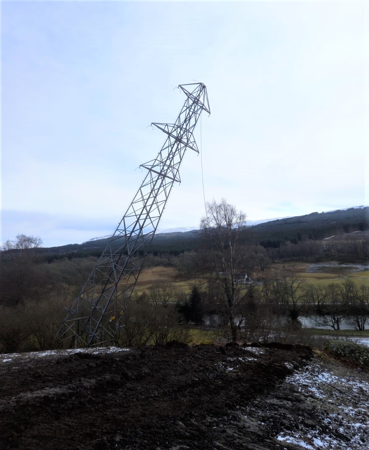 A metal transmission tower partway through falling.