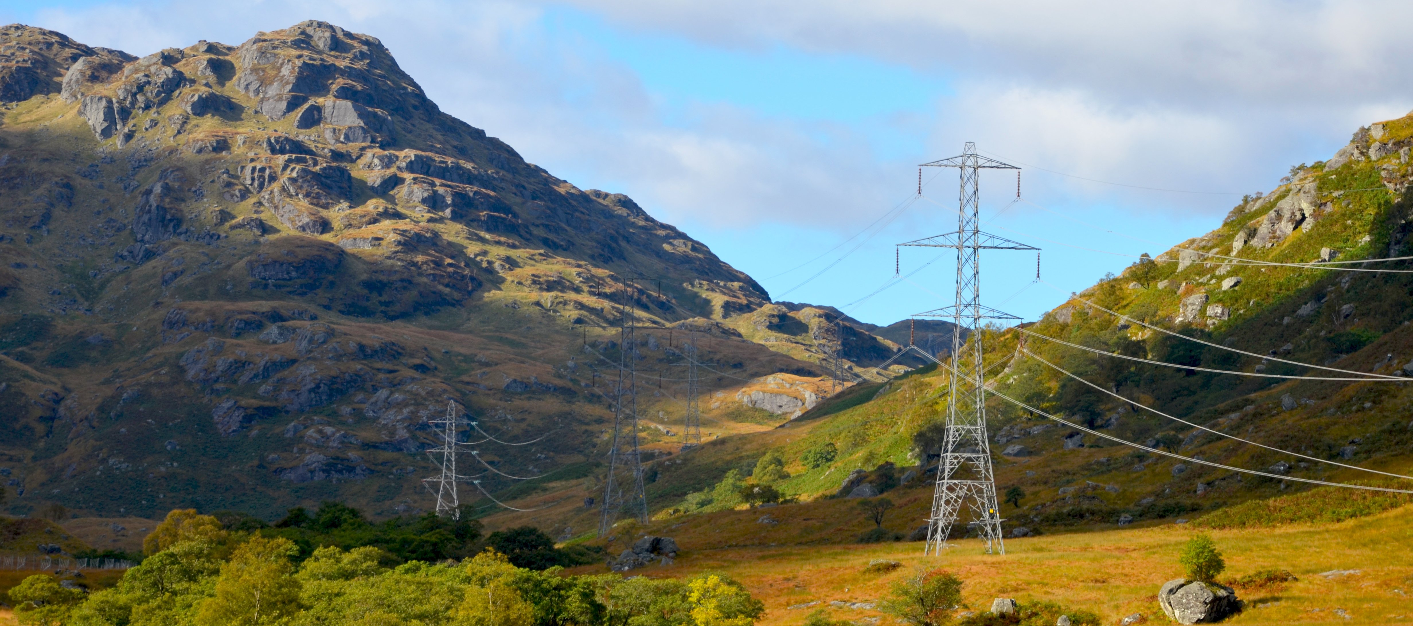 Metal transmission towers in a rocky area.