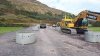 Concrete structures in two rows, construction vehicles are parked nearby.