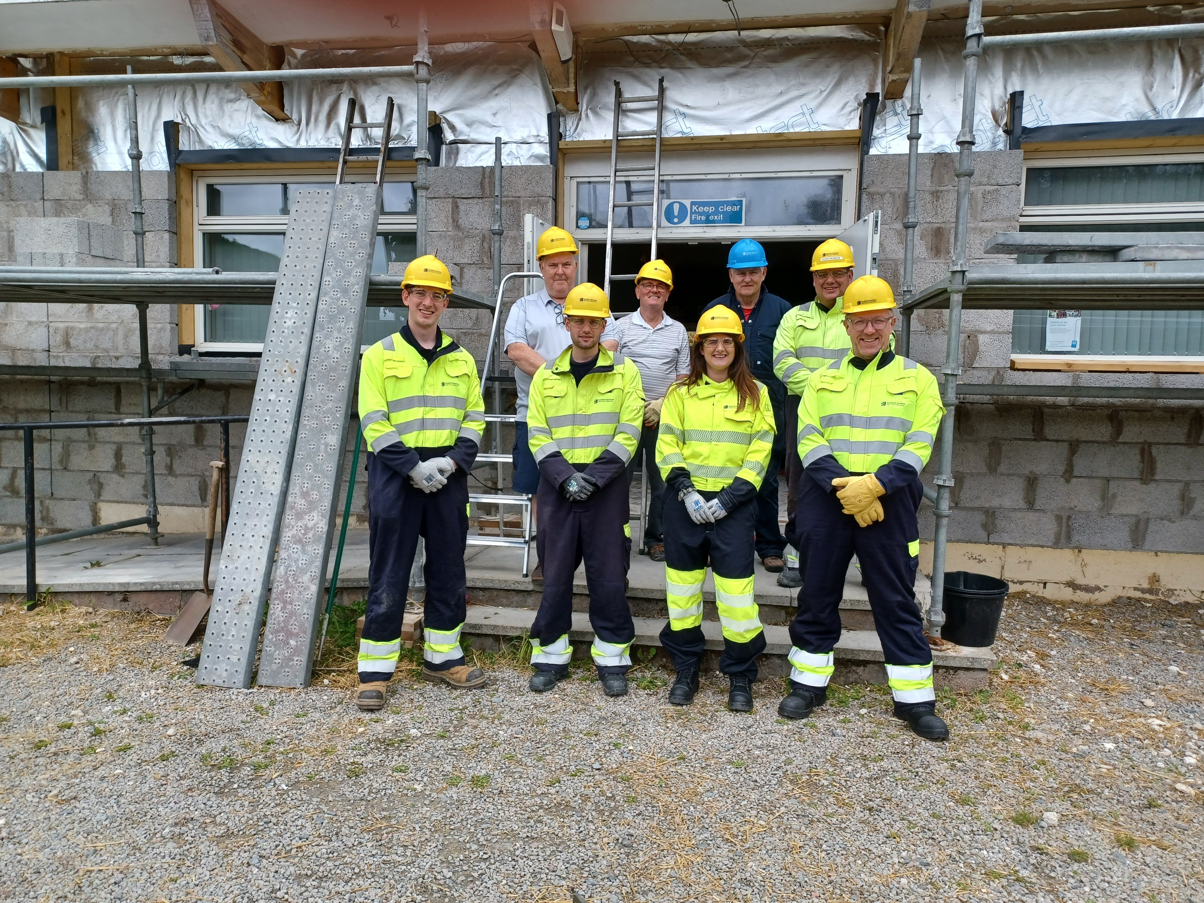 Volunteers in PPE in front of an exposed building interior.