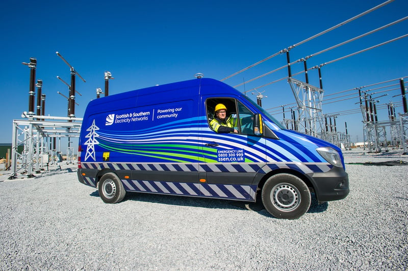 An SSEN Transmission employee in PPE at the wheel of an SSEN Transmission vehicle surrounded by substation infrastructure.