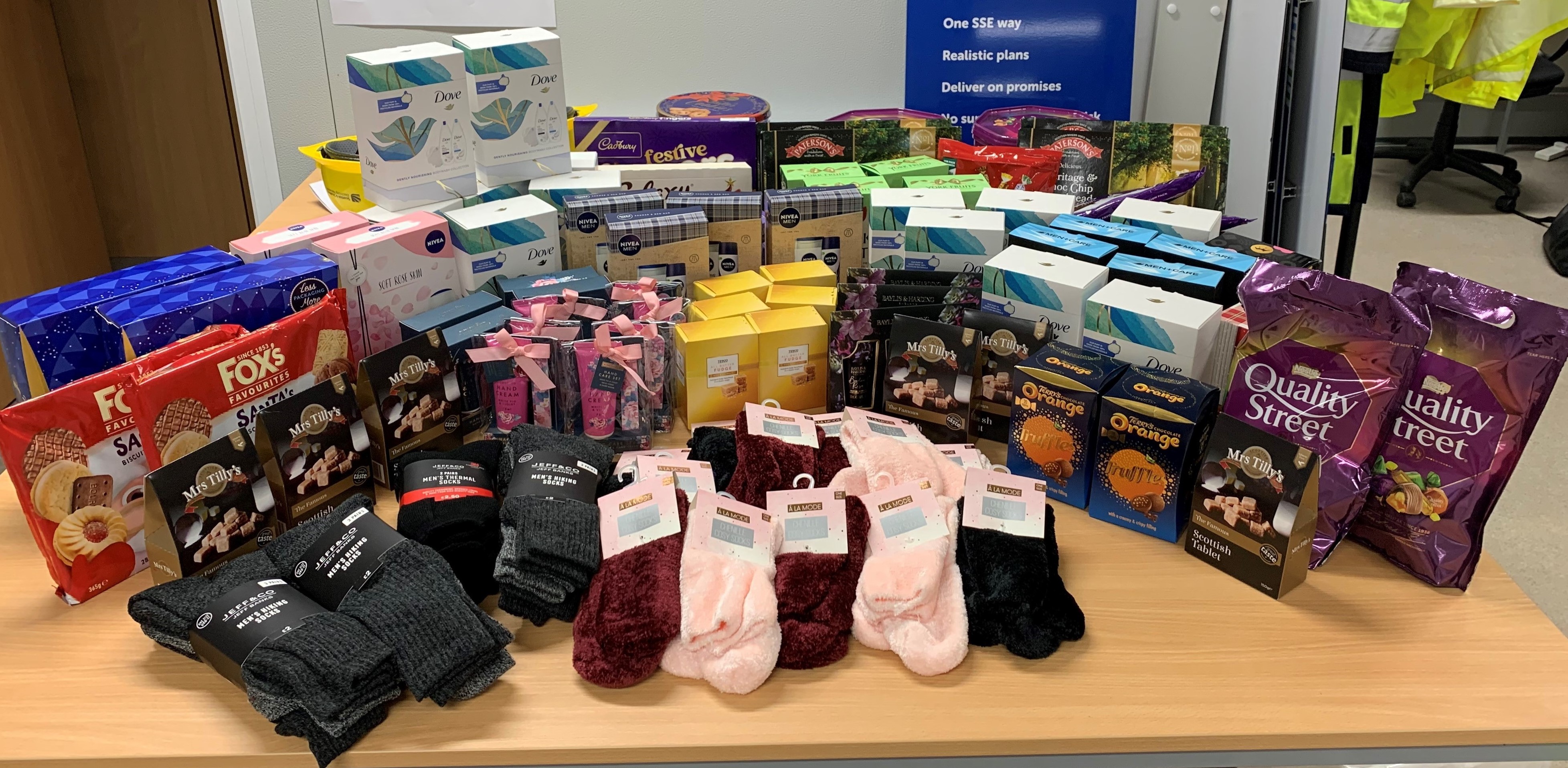 Table with assortment of chocolates, toiletires, socks and biscuits.
