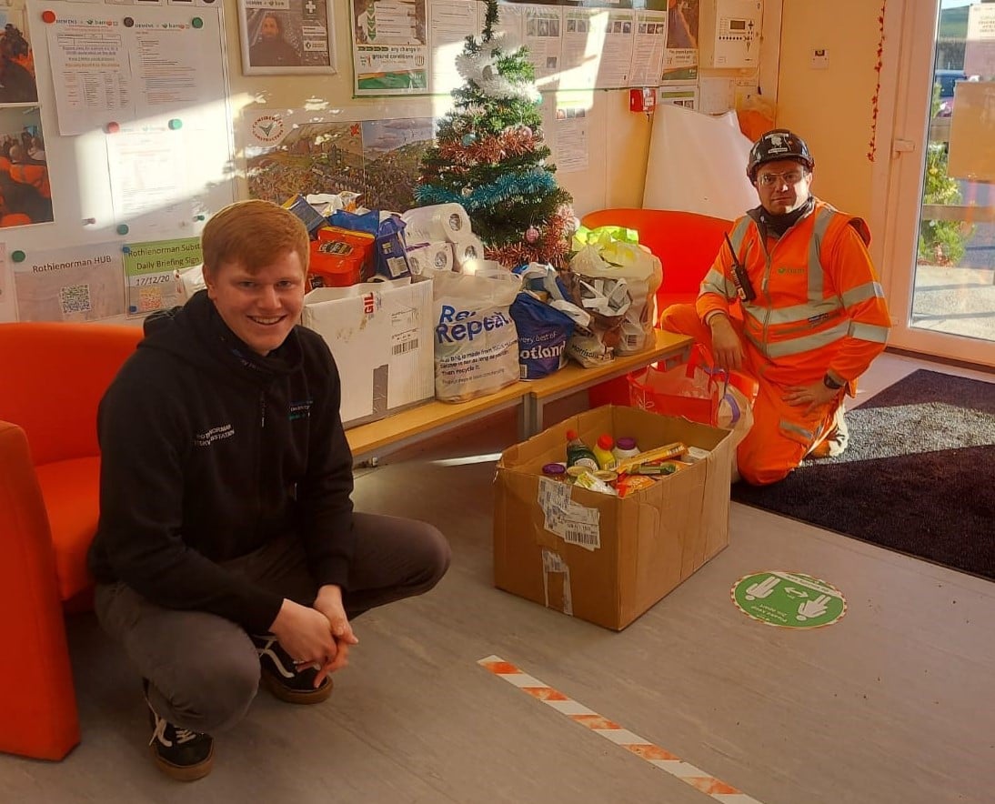 Two people standing next to box of food donations