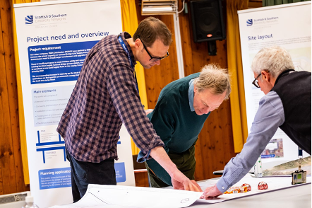 Image of public consultation event attendees and ssen transmission colleagues talking over a large map 