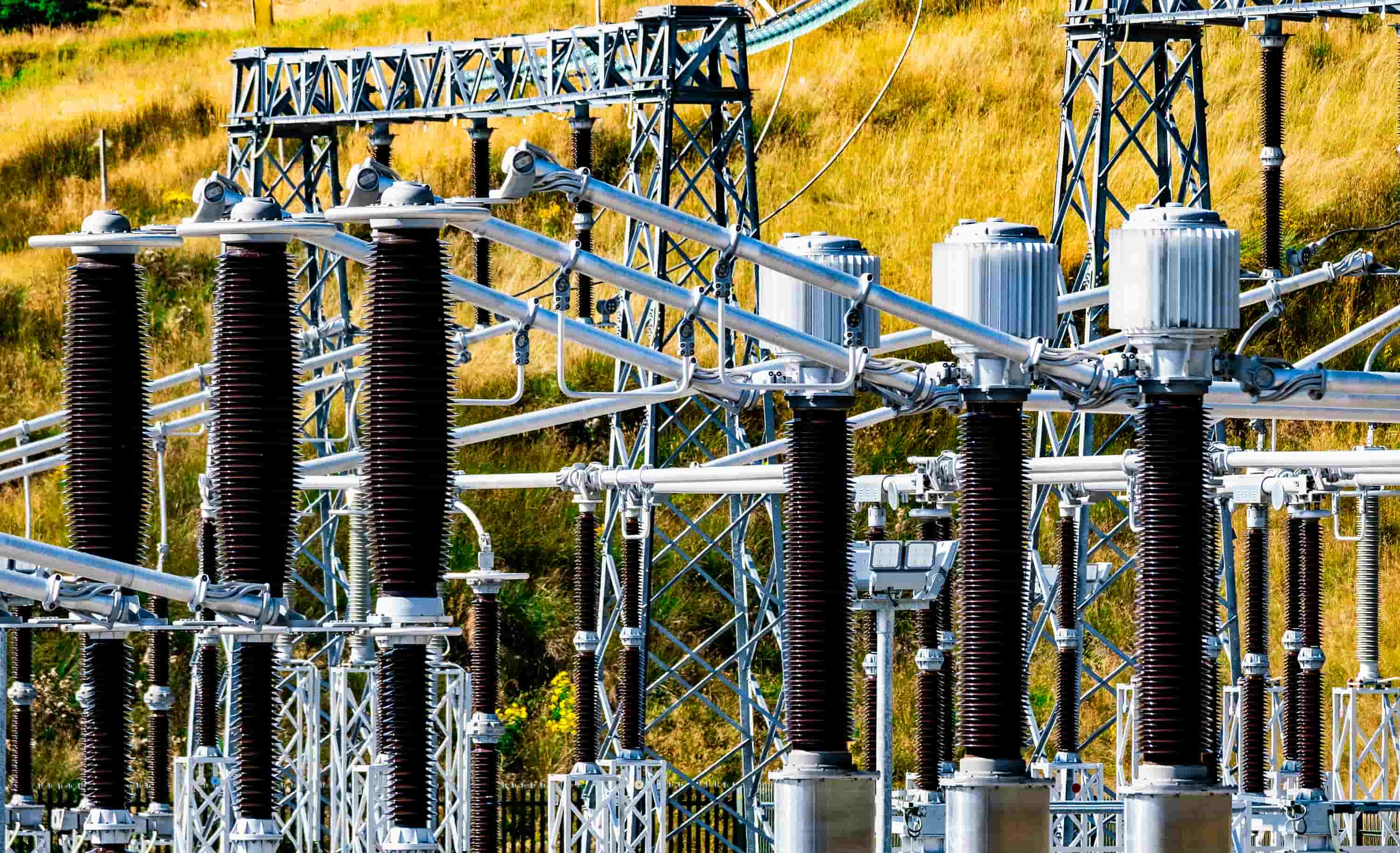 Rows of tall electrical insulators and metal connecting structures at a power substation.