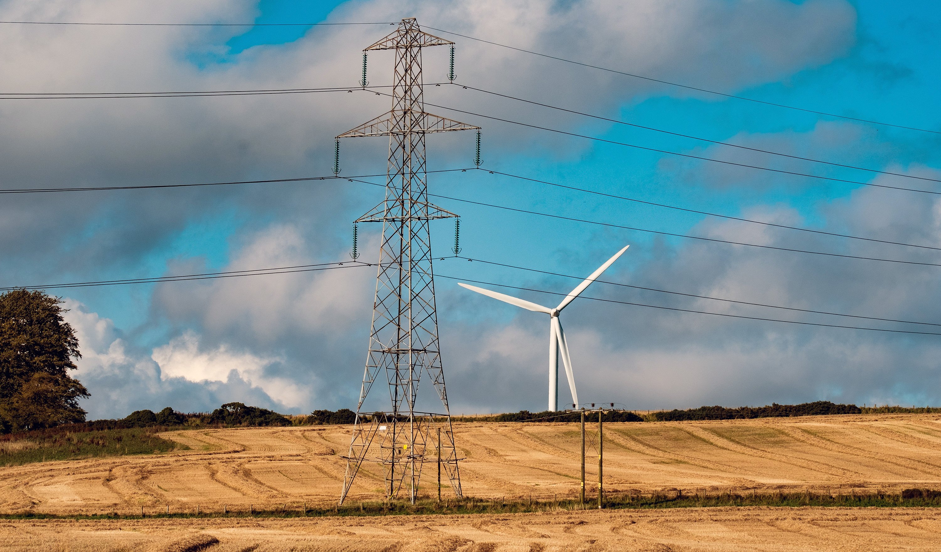 Image shows a pylon and a wind turbine